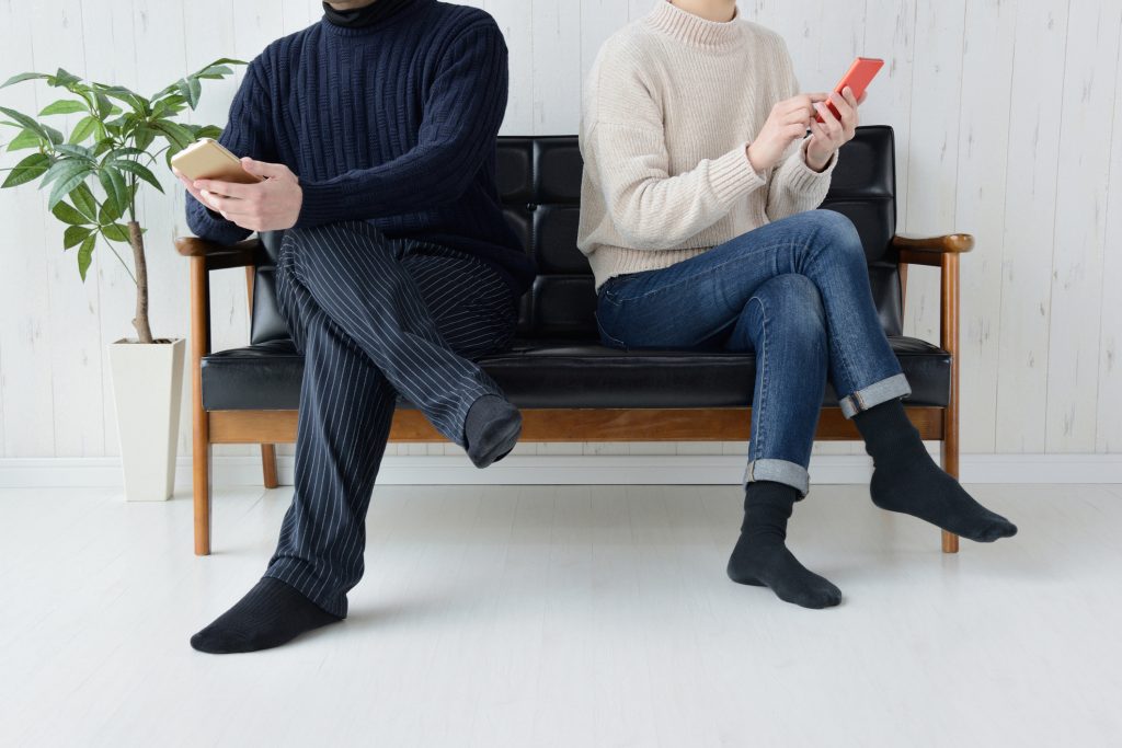 married couple ignoring each other while on smartphone