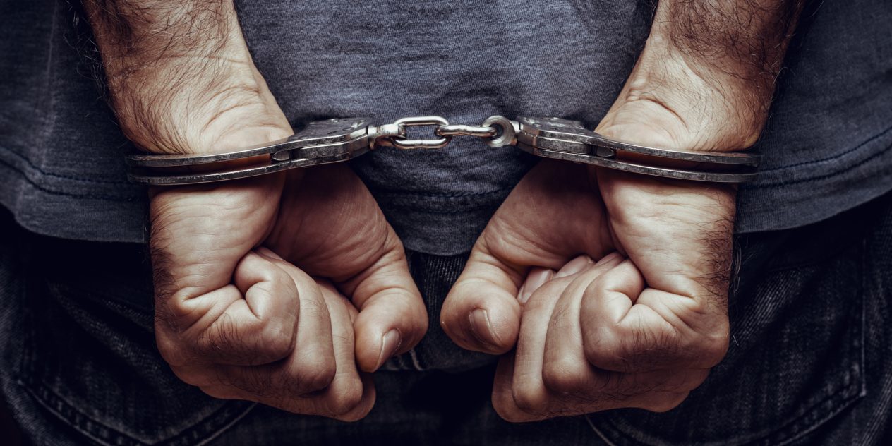 man arrested in handcuffs with hands behind his back