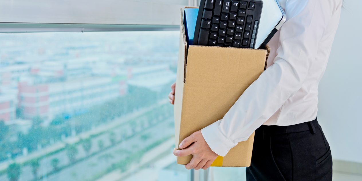 A woman holding a box in an office after seeking employment claims and aggravated damages