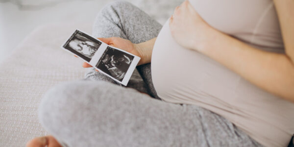 pregnant woman seeing ultrasound photo on bed